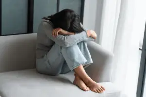 Stress et tensions représentes par une femme recroquevillée sur un canapé